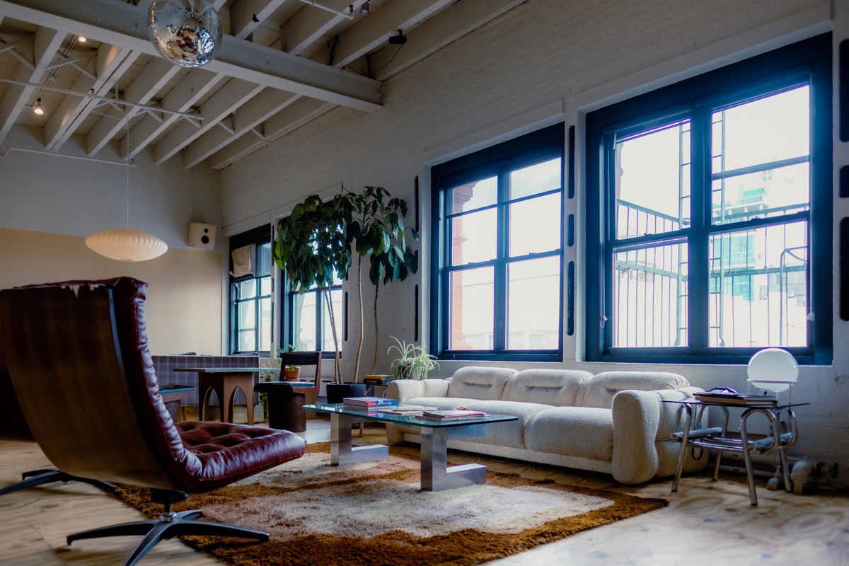 Café with cane chairs, dark walls, hanging plants, and a glass skylight