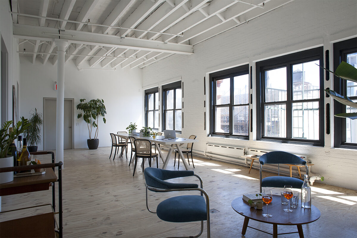 Long meeting table with red and navy chairs in a sunlit room
