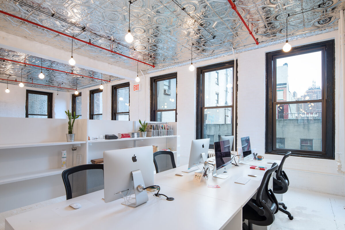 Members working at long shared desks in a sunlit room