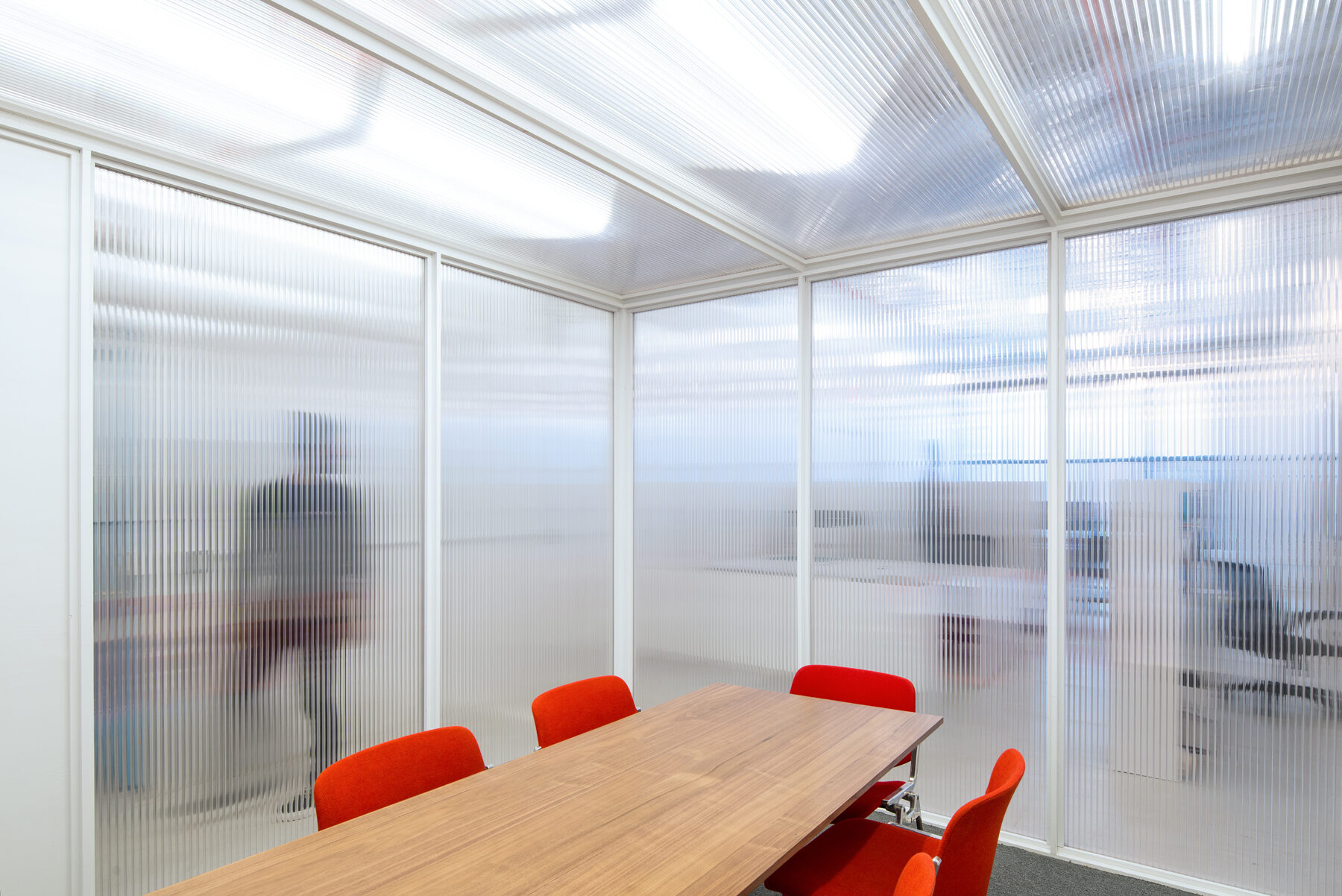 Meeting room with translucent corrugated walls and red chairs