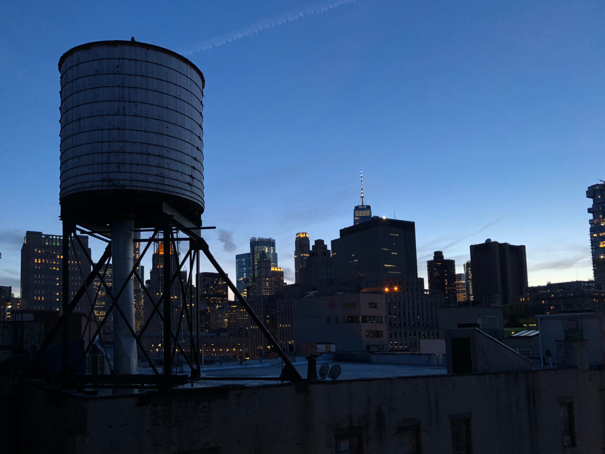 Wooden water tower on the Based In rooftop against the Manhattan skyline at dusk