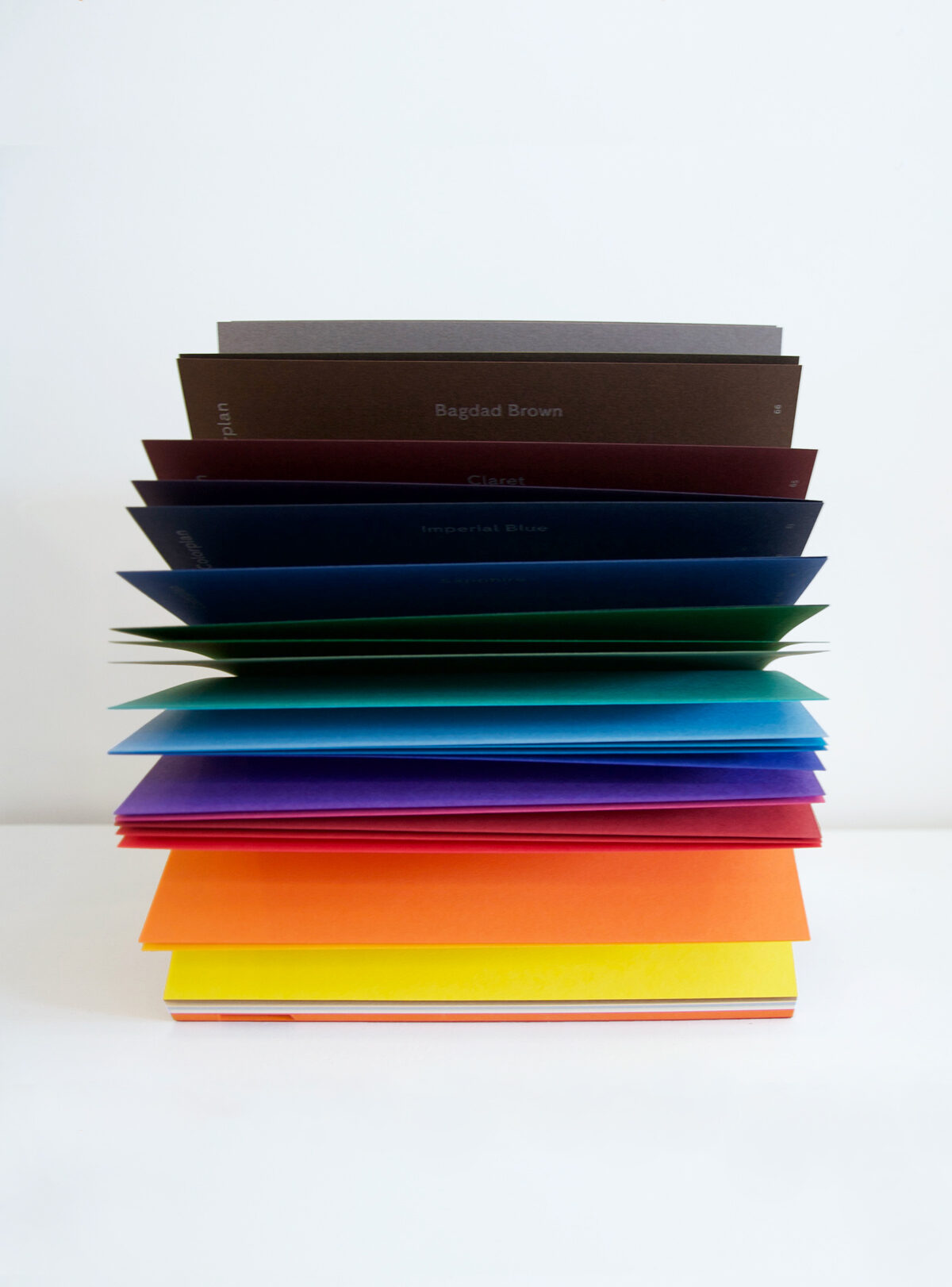 Stack of colored Colorplan paper samples on a white surface
